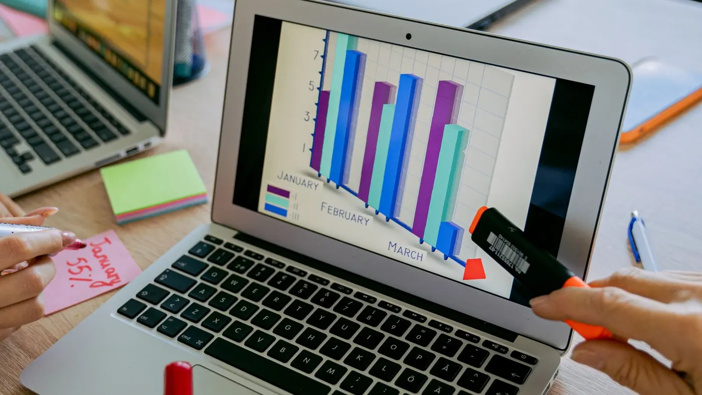 Laptop showing monthly bar charts on a desk with notes