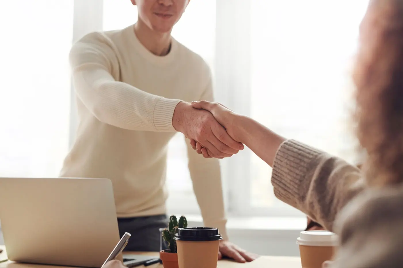 Business partners shaking hands over a signed agreement